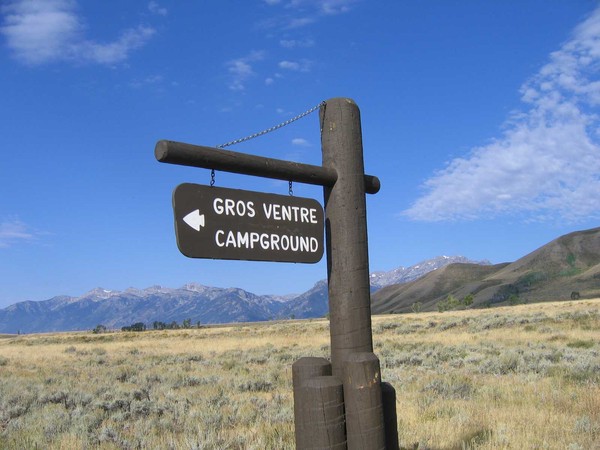 Entrance sign for Gros Ventre Campground with Blacktail Butte and the Teton Range in the distance.