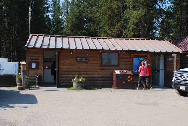small wooden office building with visitor in front and car to the side.