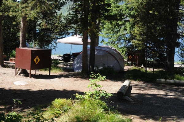 small camper trailer with canopy, bear box and picnic table with Jackson Lake beyond.
