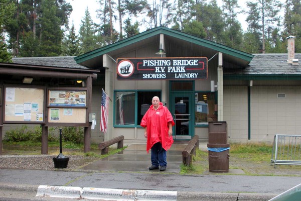Man dressed inraincoat standing in front of building.